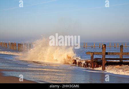 A wave crashing against eroded sea defences in winter on the North Norfolk coast at Cart Gap, Happisburgh, Norfolk, England, United Kingdom. Stock Photo