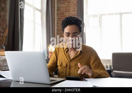 Happy young Afro American entrepreneur woman in glasses counting profit Stock Photo