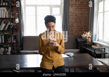 Focused African entrepreneur woman in eyeglasses reading text message Stock Photo