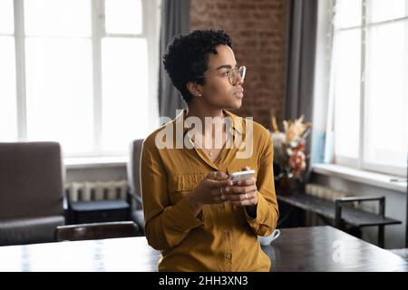 Thoughtful serious African business woman holding mobile phone Stock Photo