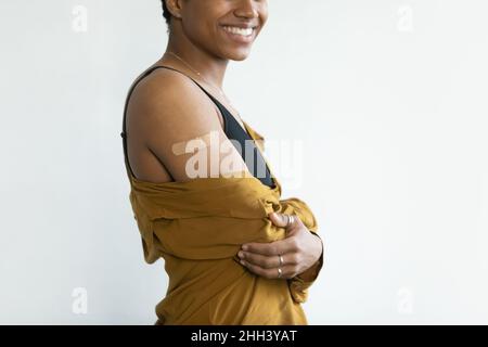 Happy Afro American lady showing shoulder with adhesive plaster Stock Photo