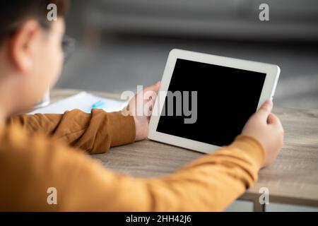 Over shoulder shot of chubby boy using digital tablet, mockup Stock Photo