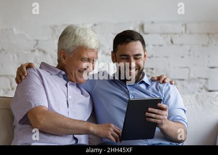 Happy adult son teaching mature father to use online app Stock Photo
