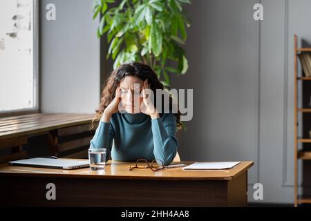 Stressed female employee feeling nervous at work, businesswoman suffering from high blood pressure Stock Photo