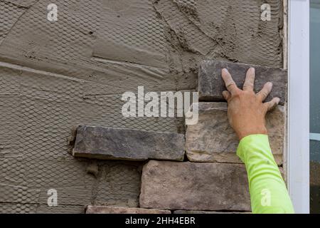 Worker making texture of wall facing with decorative stone tiles bricks Stock Photo