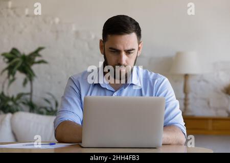 Focused millennial business man using laptop at table Stock Photo