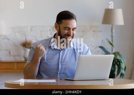 Excited happy guy getting good news, looking at laptop display Stock Photo