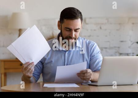 Satisfied smiling business man doing paperwork at home workplace Stock Photo