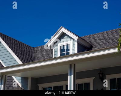White vintage windows, little room decoration on the roof of the big wooden house pastel green color on blue sky background, view from outside. Stock Photo