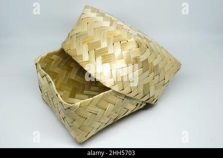 Bamboo besek is a traditional food box made of woven bamboo which is used to store goods or food. Besek is a traditional hand crafted food container. Stock Photo