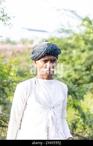 Jawai, Rajasthan, India - September 2021: Portrait of a male shepherd of the Rabari ethnic group in a national headdress and traditional white dress, Stock Photo