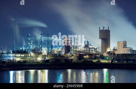 Illuminated petrochemical industry factory by a river at night Stock Photo