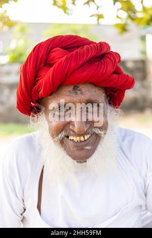 Jawai, Rajasthan, India - September 2021: Portrait of a male shepherd of the Rabari ethnic group in a national headdress and traditional white dress, Stock Photo