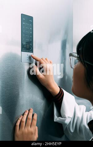 Young scientist pointing at control panel while working in laboratory Stock Photo