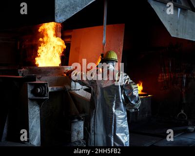 Foundry worker burning metal in furnace at workshop Stock Photo