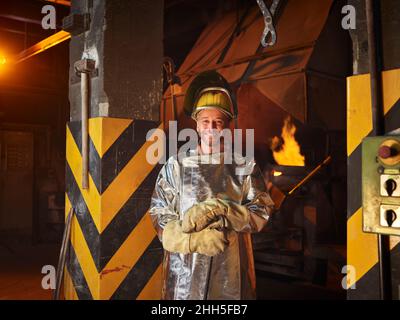 Smiling metal worker wearing protective workwear in steel mill Stock Photo