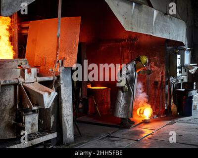 Craftsperson pouring burning metal while working in industry Stock Photo