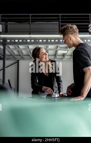 Businesswoman discussing with trainee in industial hall Stock Photo