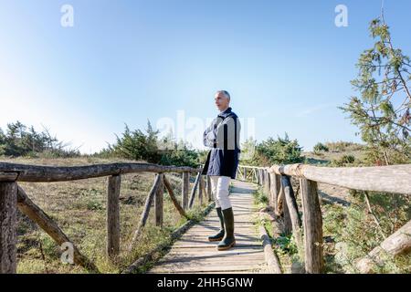 Man standing with arms crossed on wooden bridge Stock Photo