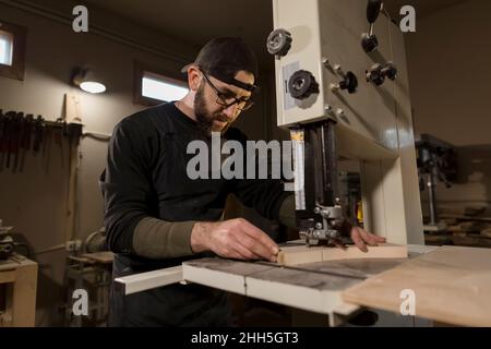 Woodworker working on band saw in workshop Stock Photo