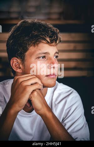 Thoughtful young man with hands clasped looking away Stock Photo