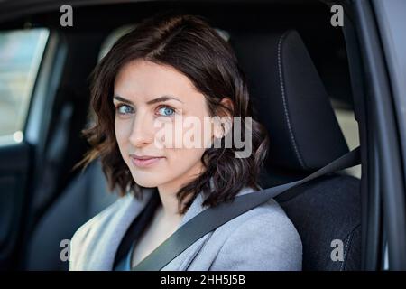 Smiling woman sitting on driver seat in electric car Stock Photo