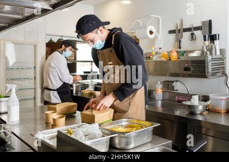 Chefs preparing takeaway food in kitchen at restaurant Stock Photo