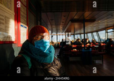 Senior woman with protective face mask in ferry during COVID-19 Stock Photo