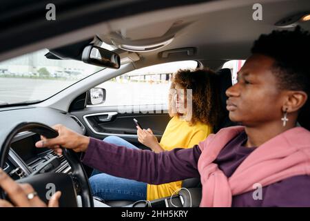 Young man driving and woman using smart phone sitting in car Stock Photo