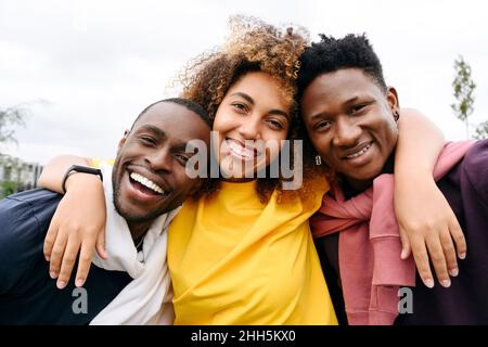 Happy woman with arms around friends outdoors Stock Photo
