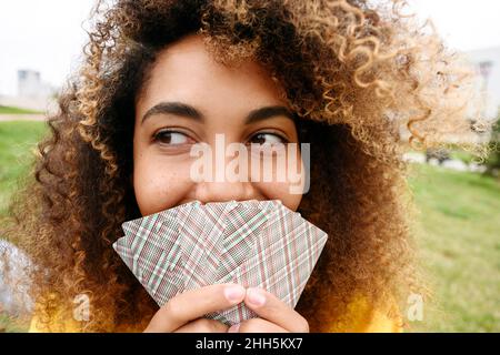 Young woman covering mouth with playing cards Stock Photo