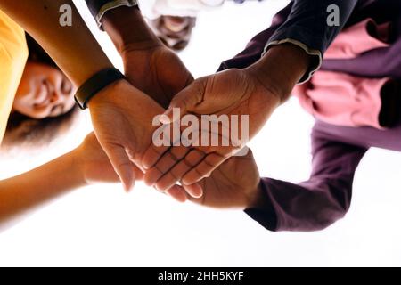 Multiracial young friends stacking hands Stock Photo