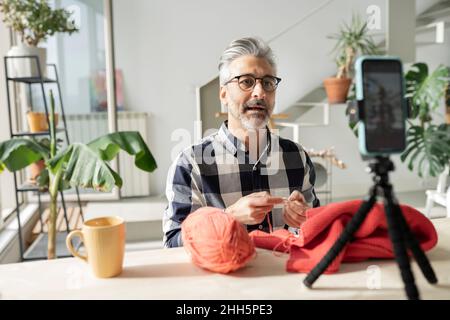 Man making video tutorial on knitting using smart phone at home Stock Photo