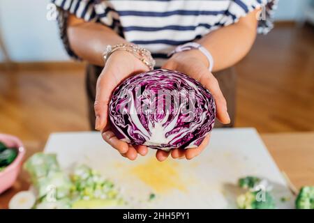 Woman holding halved red cabbage at home Stock Photo