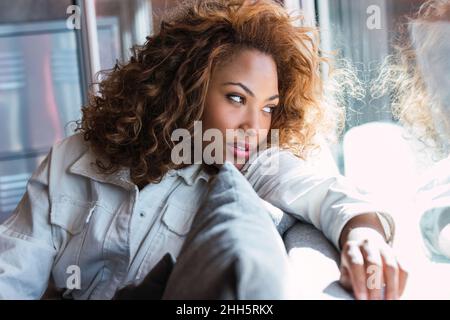 Thoughtful young woman looking out of window Stock Photo
