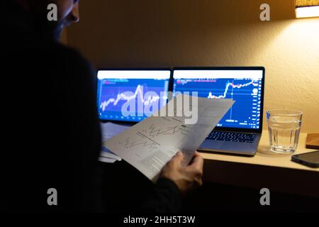 Businessman reviewing documents trading cryptocurrency on laptop at home office Stock Photo
