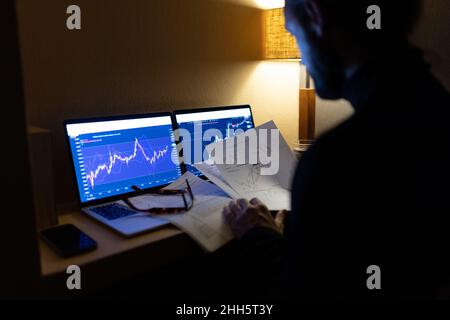 Businessman with documents analyzing stock market data on laptop at home office Stock Photo