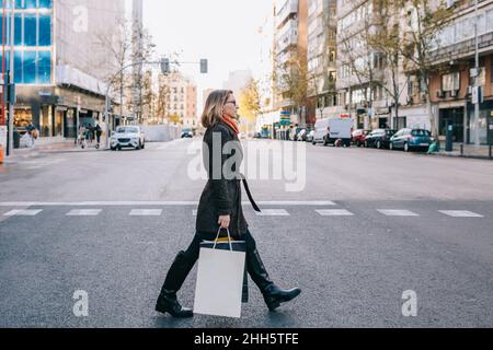 Woman with shopping bags crossing road in city Stock Photo