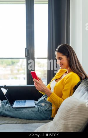 Young woman using smart phone while working at home Stock Photo
