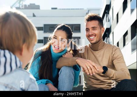 Cheerful parents talking with baby boy in city Stock Photo