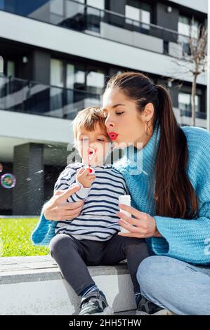 Mother and son blowing soap bubbles in city Stock Photo