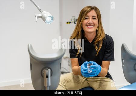 Smiling gynecologist wearing protective gloves sitting in clinic Stock Photo