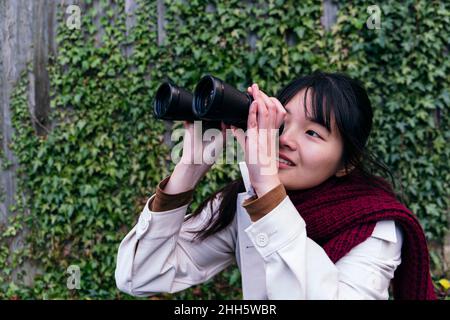 Smiling young woman looking through binoculars Stock Photo