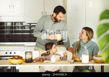 Man talking to woman sitting by daughter at breakfast table Stock Photo