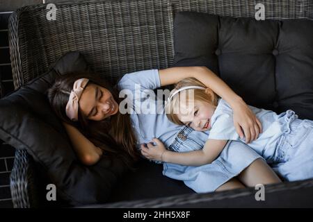 Happy siblings lying on sofa at patio Stock Photo