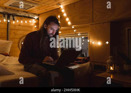 Young man using laptop in van on Christmas vacation Stock Photo