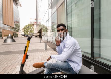 Thoughtful man talking on smart phone in front of building Stock Photo