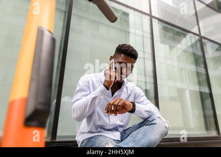 Young man checking time and talking on smart phone Stock Photo