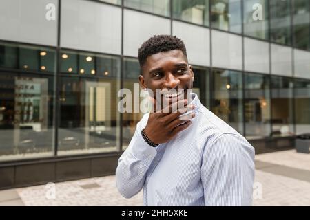 Thoughtful smiling man with hand on chin Stock Photo