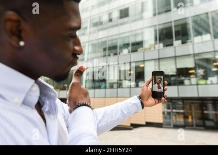 Man doing thumbs up taking selfie through mobile phone Stock Photo